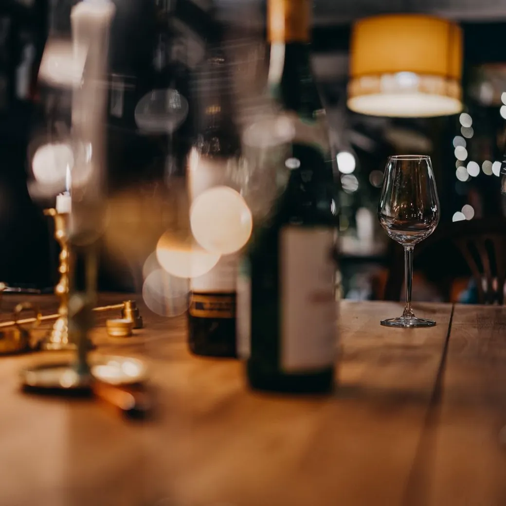 Copa de vino y palmatoria con vela sobre la mesa de madera
